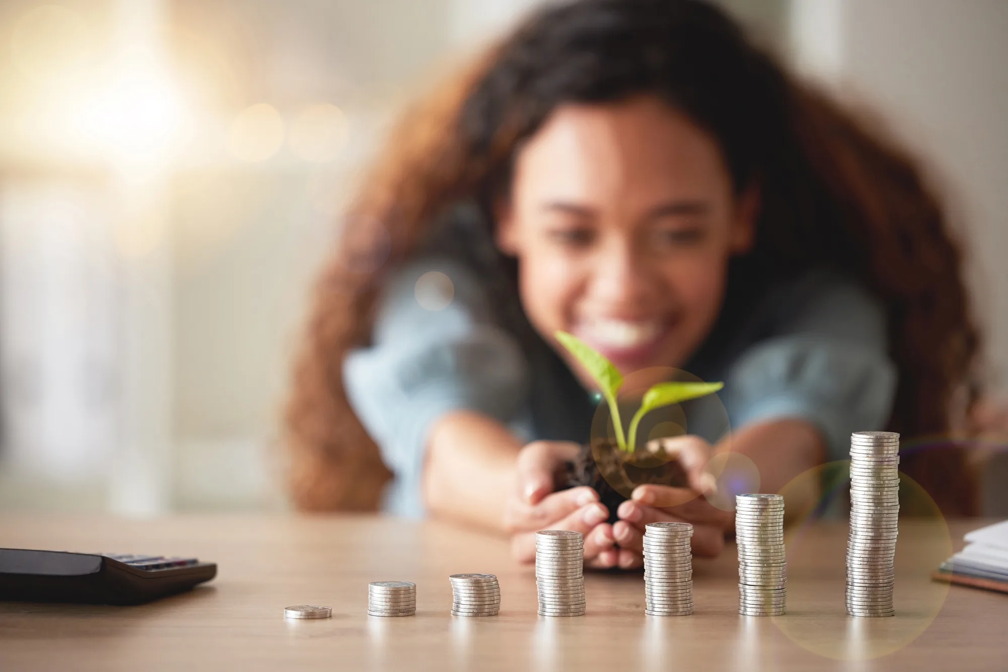 Smiling member watching her savings grow, with rising stacks of coins on the table